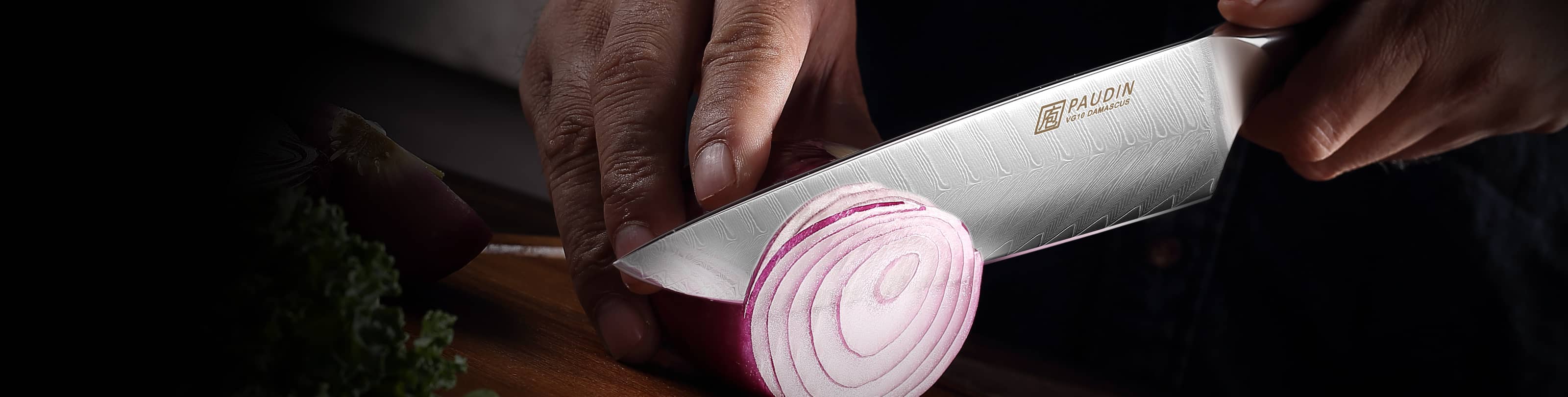 Close-up of a Paudin Damascus knife slicing a red onion on a cutting board.slider_item_qBbydQ